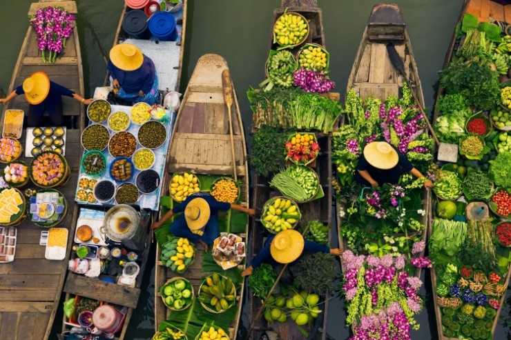 Floating market vendors, Bangkok, Thailand Floating markets are a common tradition throughout Southeast Asia where the numerous rivers and waterways are a primary means of transportation and commerce between villages. In this overhead view, Bangkok vendors draw their boats together to exchange a colorful, tasty array of goods, Thailand.