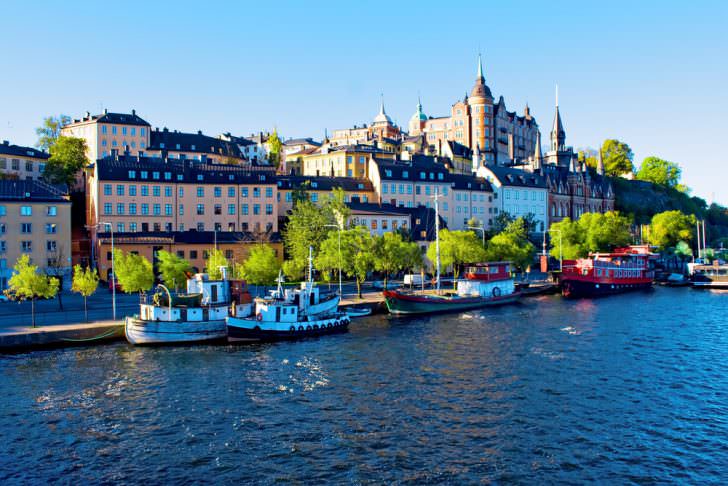 Sweden Old city buildings and old boats on water under blue sky