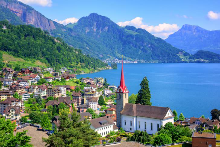 Little swiss town with gothic church on Lake Lucerne and Alps mountain, Switzerland