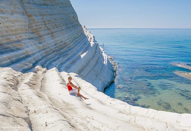 Woman sitting on a slope of white cliff called Scala dei Turchi in Sicily, Italy