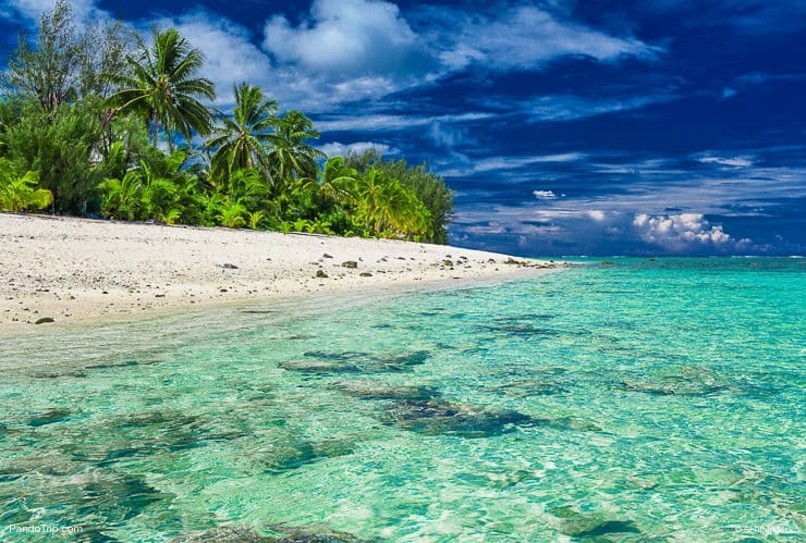 Beach with white sand and black rocks on Rarotonga, Cook Islands