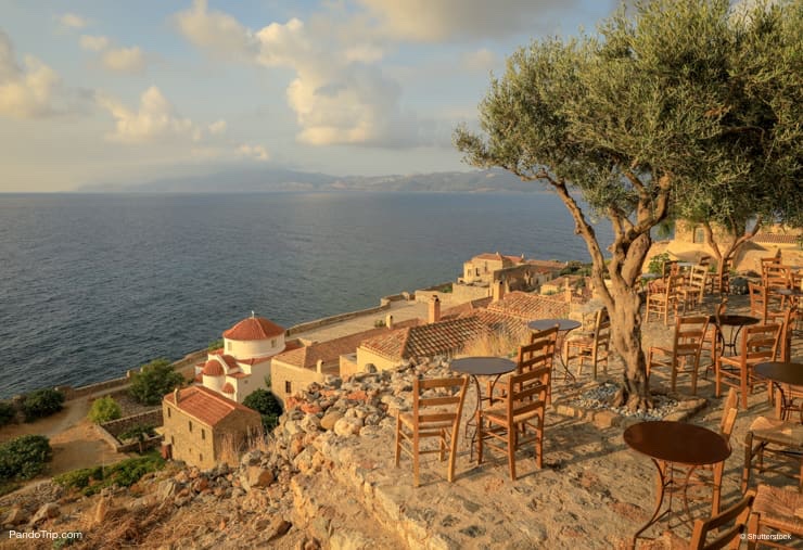 Traditional Greek cafe with olive trees in Monemvasia, Peloponnese, Greece, June 2018. Horizontal