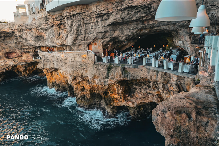 Exterior view of Grotta Palazzese, an Italian restaurant in a cave, built into the rocky cliffside overlooking the Adriatic Sea