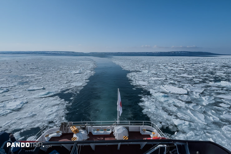 Aurora ship's rear deck with a Japanese flag, capturing the icy trail left behind