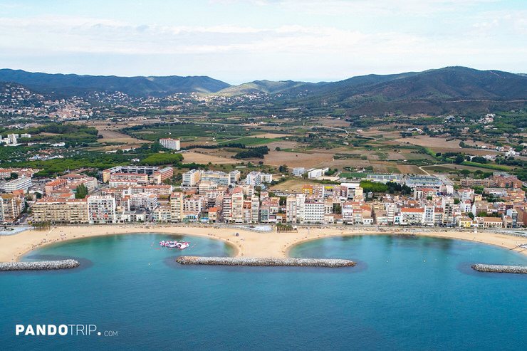 Aerial view of Sant Antoni de Calonge with Sant Antoni Beach, Seafront Promenade, and the Gavarres Hills in the background