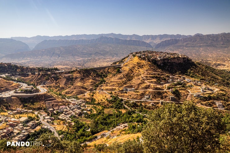 Wide-angle shot of Amedi town on a hilltop surrounded by winding roads and mountainous terrain