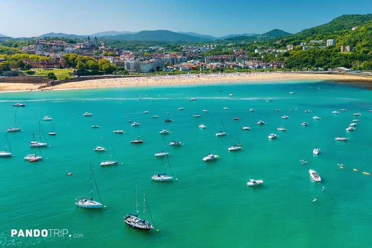Sailboats anchored in turquoise waters near Ondarreta Beach in San Sebastián, Spain