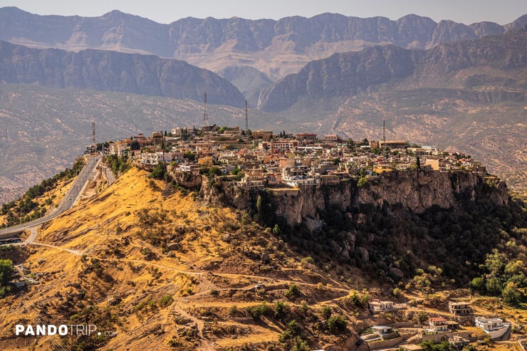 Close-up of buildings in Amedi built along the cliff edge with mountains in the background