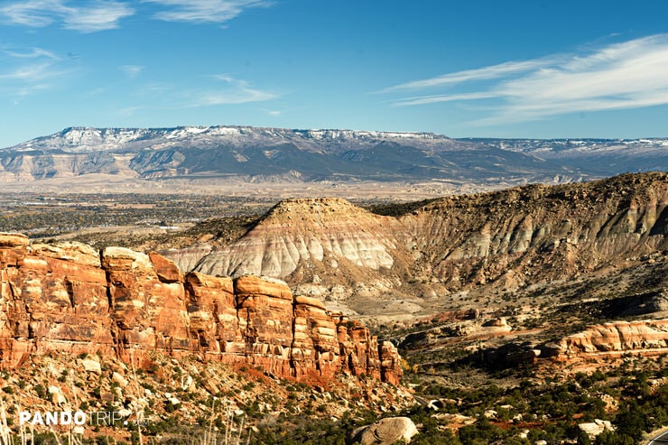 Colorful desert buttes and rock formations with snow-capped Grand Mesa in the distance