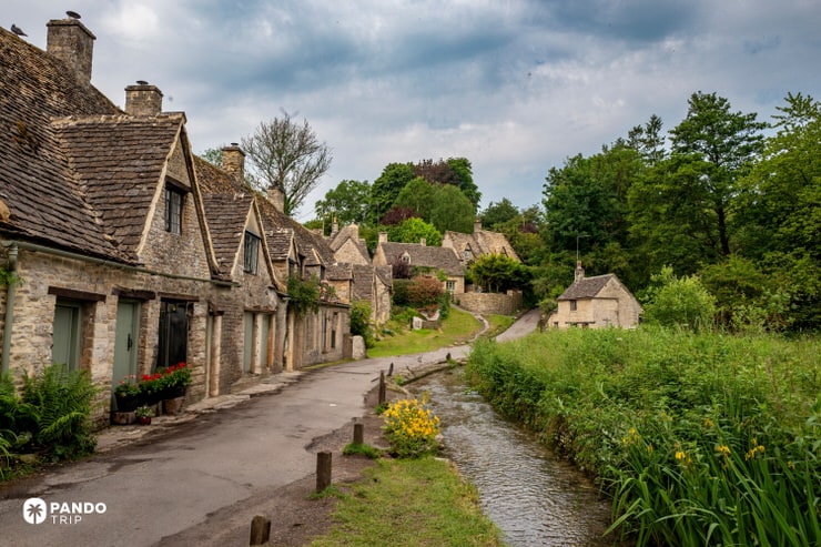 Arlington Row Bibury with river bend, cottages and cloudy summer sky