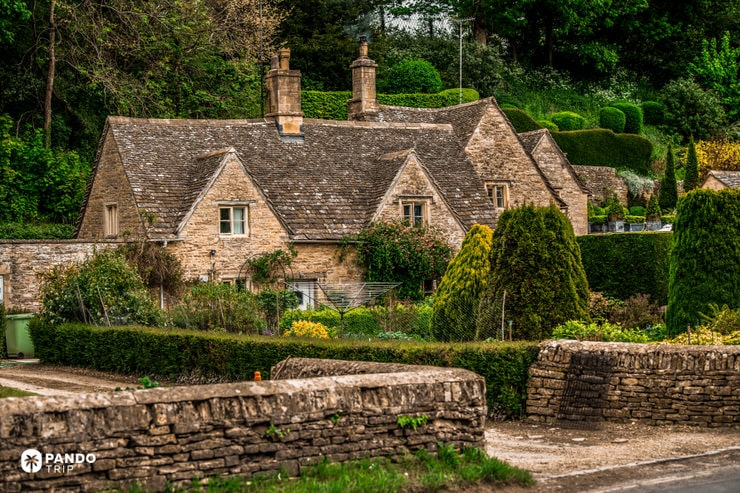 Stone cottage in Bibury framed by neatly clipped topiary and hedges