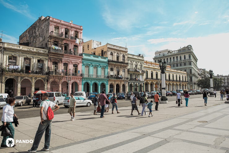 Street in Old Havana lined with pastel-colored colonial buildings and people walking