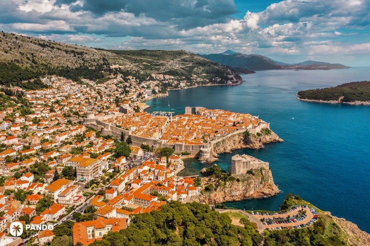 Elevated view of Dubrovnik’s walled old town, surrounded by the blue Adriatic Sea and green cliffs