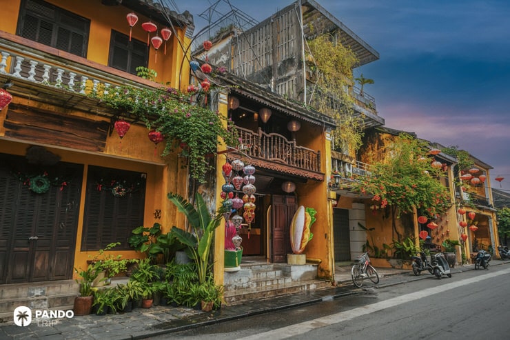 Traditional Vietnamese buildings and red lanterns lighting a quiet street in Hoi An during dusk