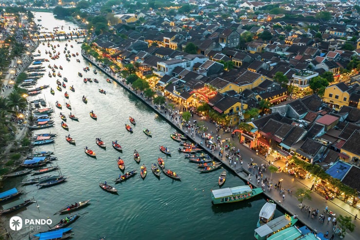 Aerial view of colorful boats with lanterns floating along Hoi An’s river promenade at dusk
