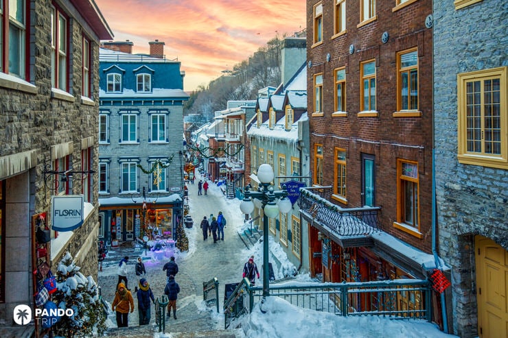 Snow-covered pedestrian street in Old Quebec with historic stone buildings and Christmas decorations