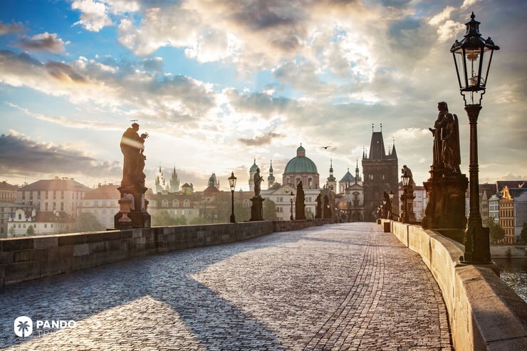 Cobbled Charles Bridge at sunset with Baroque statues and Prague’s skyline in the background