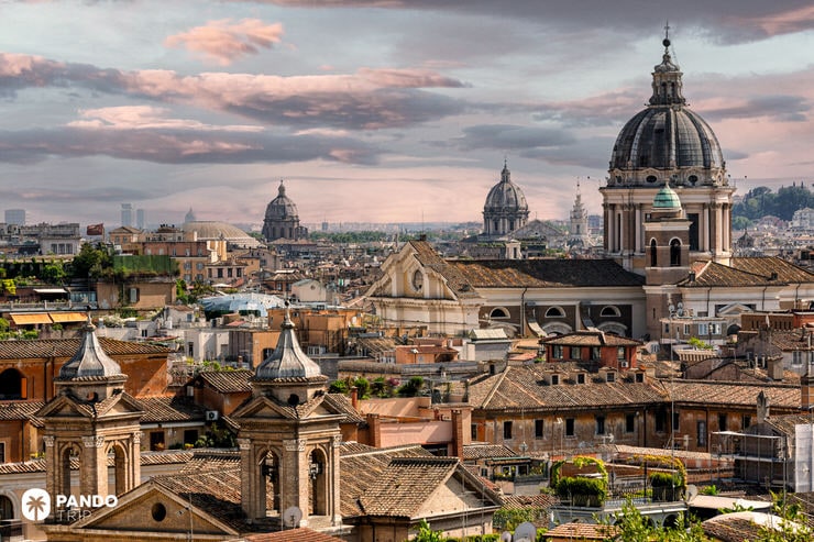 View over Rome’s rooftops with Baroque church domes and terracotta tiles at sunset