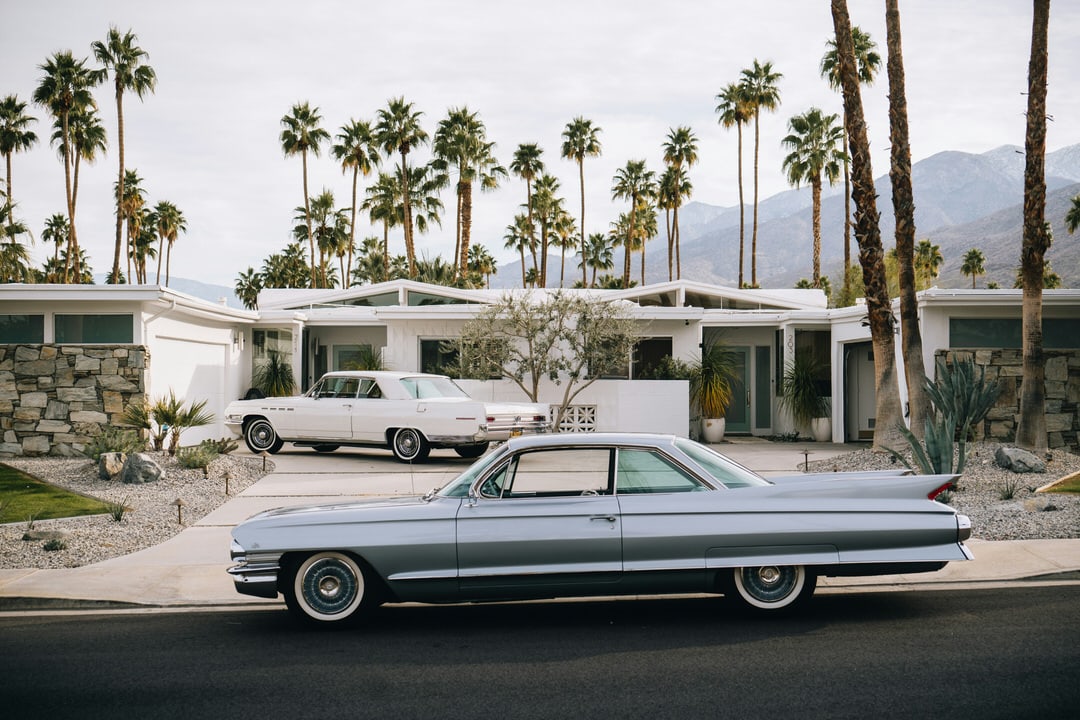 Vintage silver Cadillac parked in front of a white mid-century modern Alexander home in Palm Springs.