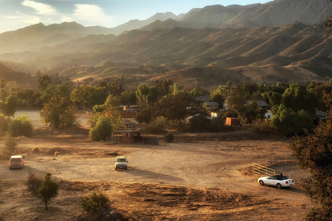 Dusty trailhead parking area in Ojai with mountains in the background and a vintage car parked.