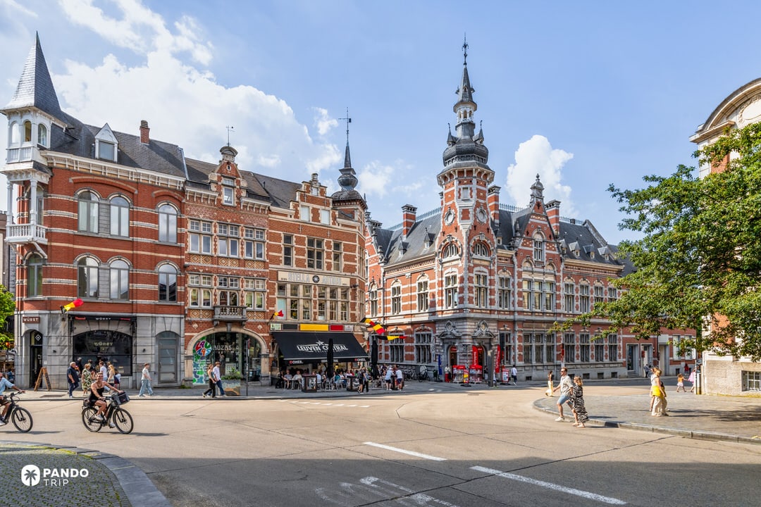 Historic square in Leuven with ornate 19th-century façades and corner turret building