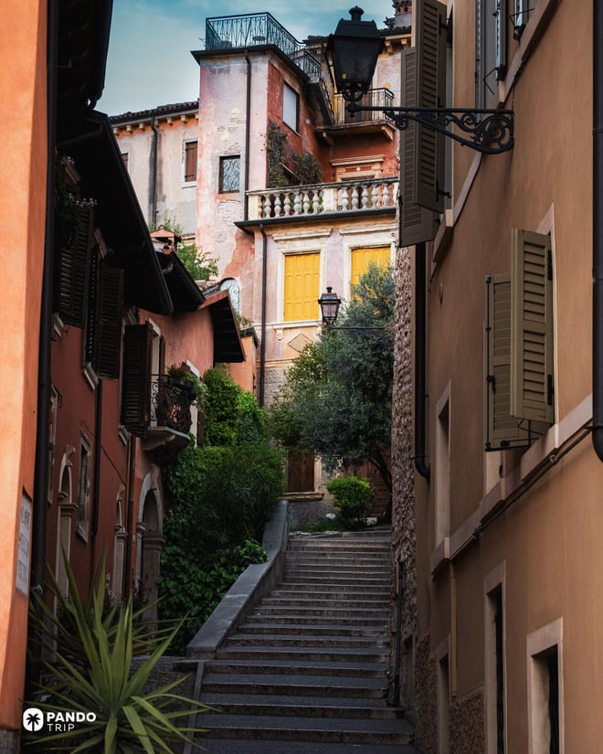 A quiet, narrow cobblestone street in Verona with steep stairs flanked by colorful historic buildings.
