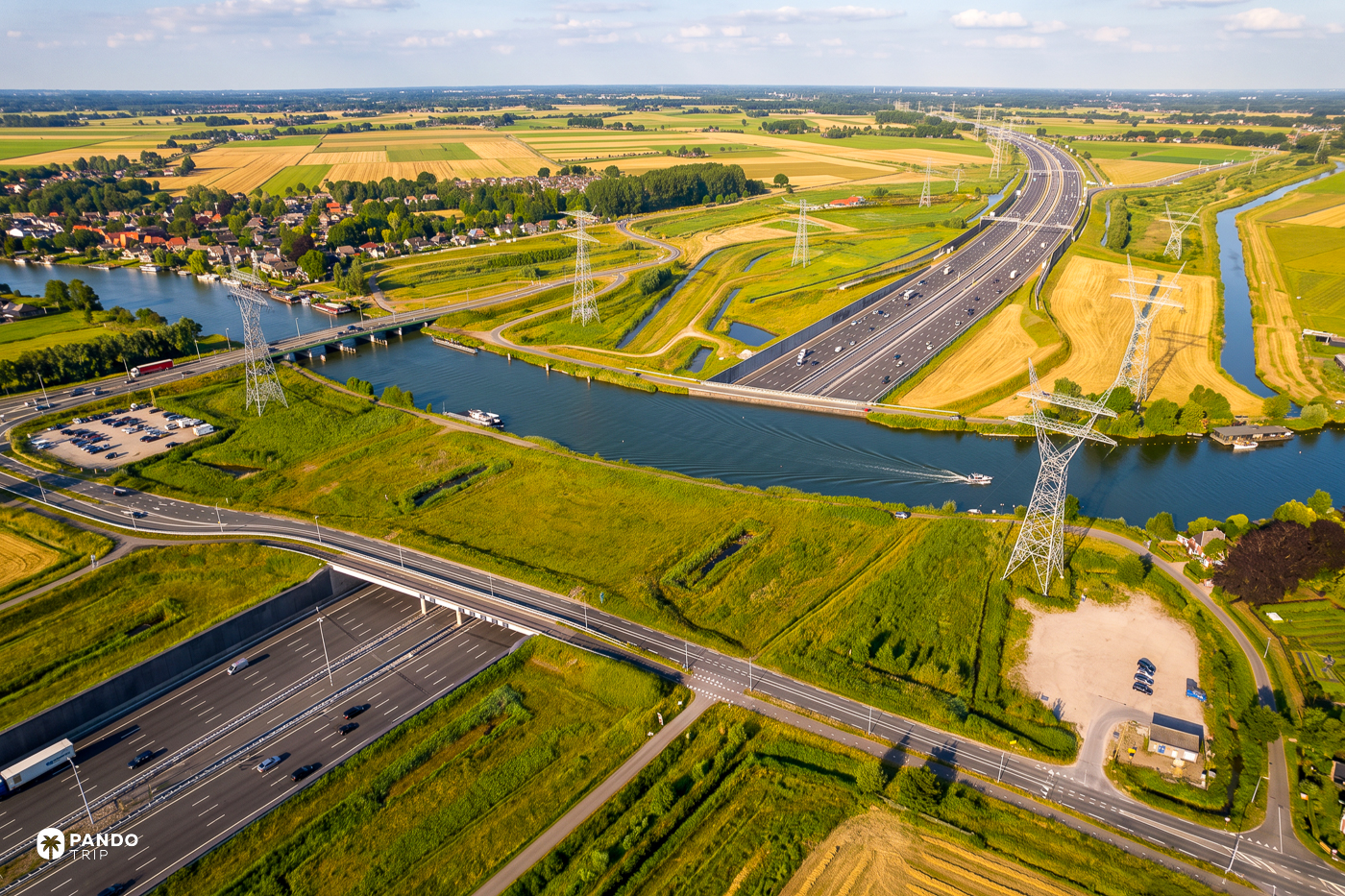 Aerial view of Aquaduct Vechtzicht at Muiden, where the river Vecht crosses over the twelve lanes of the A1 motorway between polder fields and pylons.