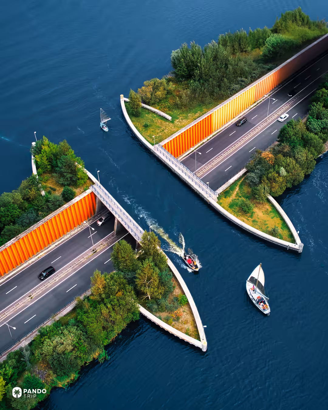 Aerial view of the Aquaduct Veluwemeer, a small sailing dinghy and a motorboat approaching the water channel between the orange retaining walls of the N302.