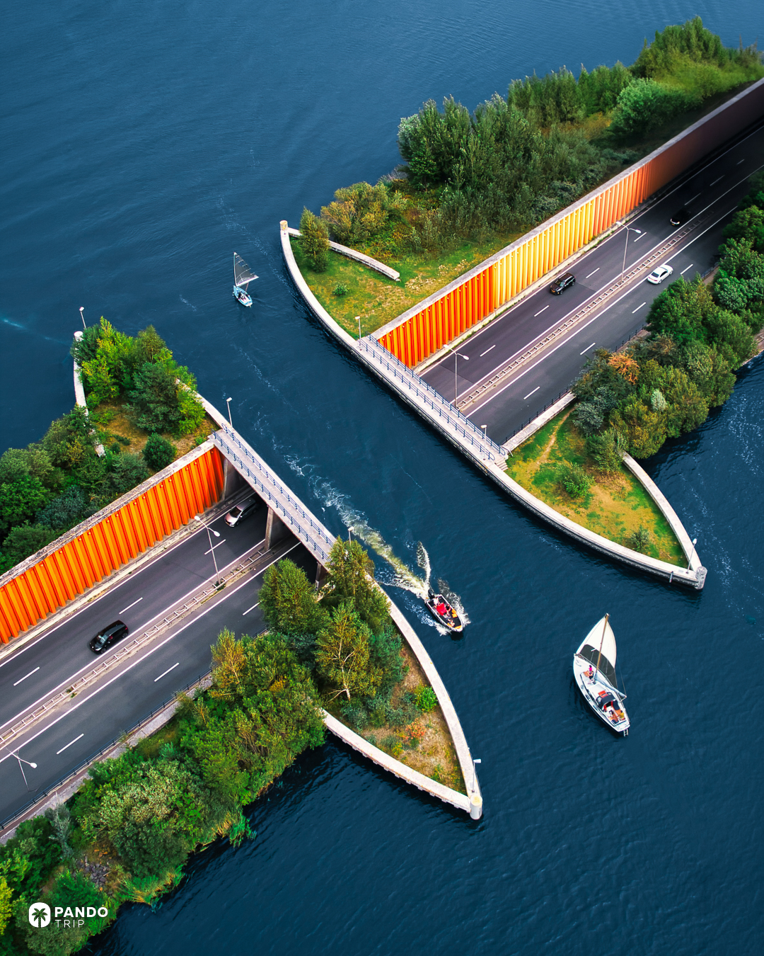 Aerial view of the Aquaduct Veluwemeer, a small sailing dinghy and a motorboat approaching the water channel between the orange retaining walls of the N302.