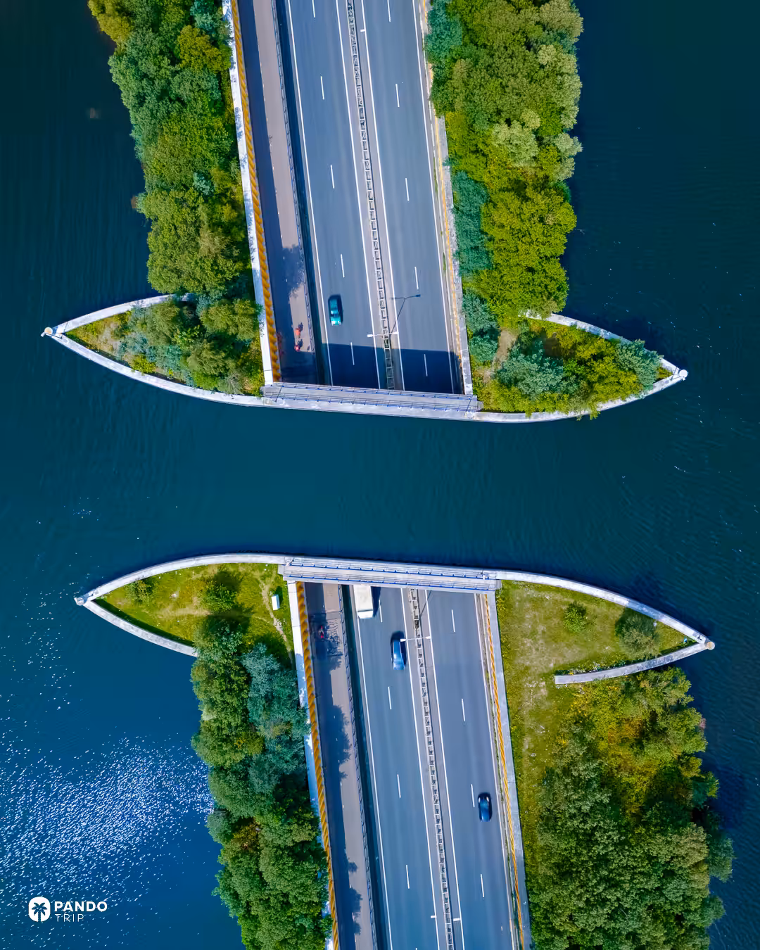 Overhead view of the Aquaduct Veluwemeer showing both carriageways of the N302 and the separate cycle path, with the empty water channel between the tree-covered banks.