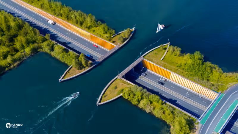 Aerial view of the Aquaduct Veluwemeer near Harderwijk, a sailing yacht crossing the water above the N302 as cars pass along the sunken road below.