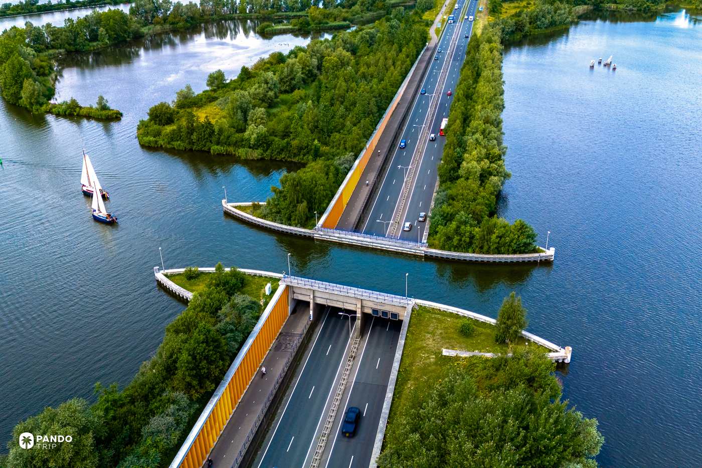 The N302 descending into the Aquaduct Veluwemeer tunnel mouth, a sailing barge on the lake to the left and a cyclist on the separate cycle path.