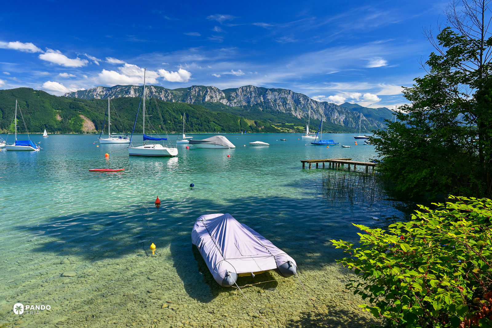 Moored dinghies over the pale stony shallows of the Attersee, with the Hollengebirge behind.