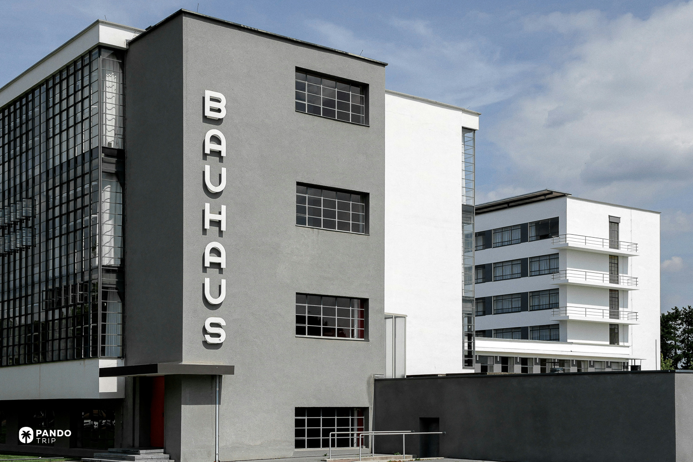 Vertical BAUHAUS lettering on the grey entrance block, with the white studio wing and its balconies behind.