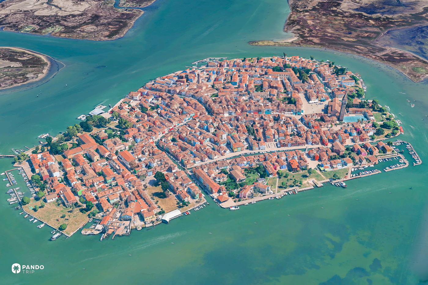 Satellite view of Burano, an oval of terracotta rooftops cut by canals in the Venetian lagoon.