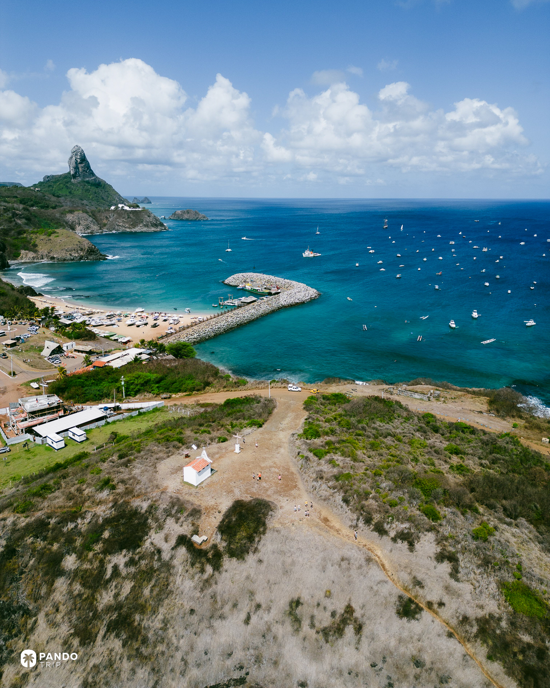 Boats moored off the beach at Vila dos Remedios with the peak of Morro do Pico behind, Fernando de Noronha.