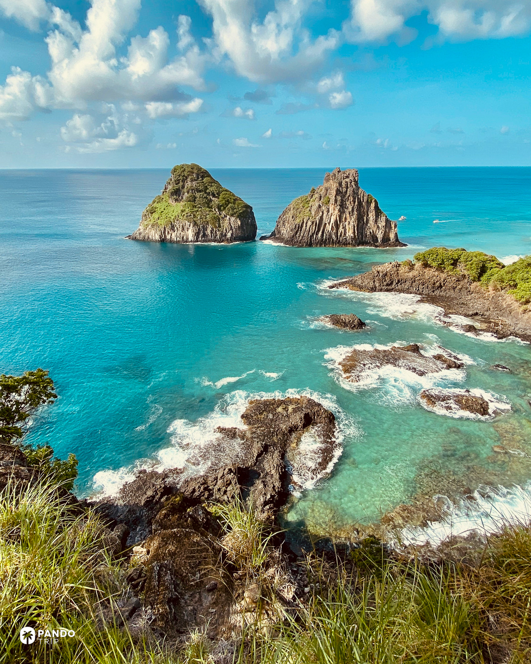 The twin rock stacks of Morro Dois Irmaos standing off a reef-broken bay, Fernando de Noronha.