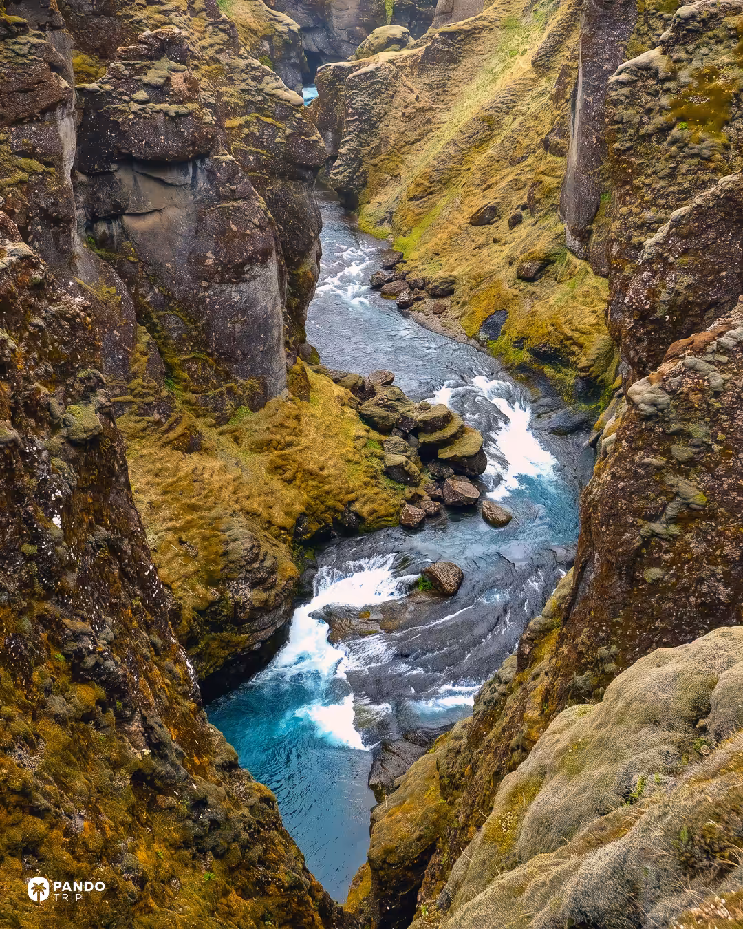 Turquoise rapids of the Fjaðrá running between close, moss-topped canyon walls.
