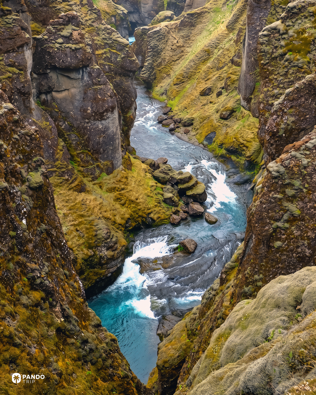 Turquoise rapids of the Fjaðrá running between close, moss-topped canyon walls.