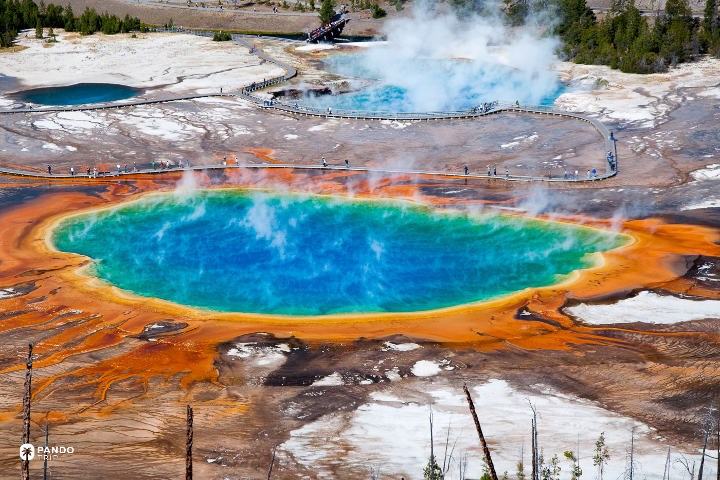 Grand Prismatic Spring seen from the overlook trail, its orange and blue rings behind a boardwalk of visitors.