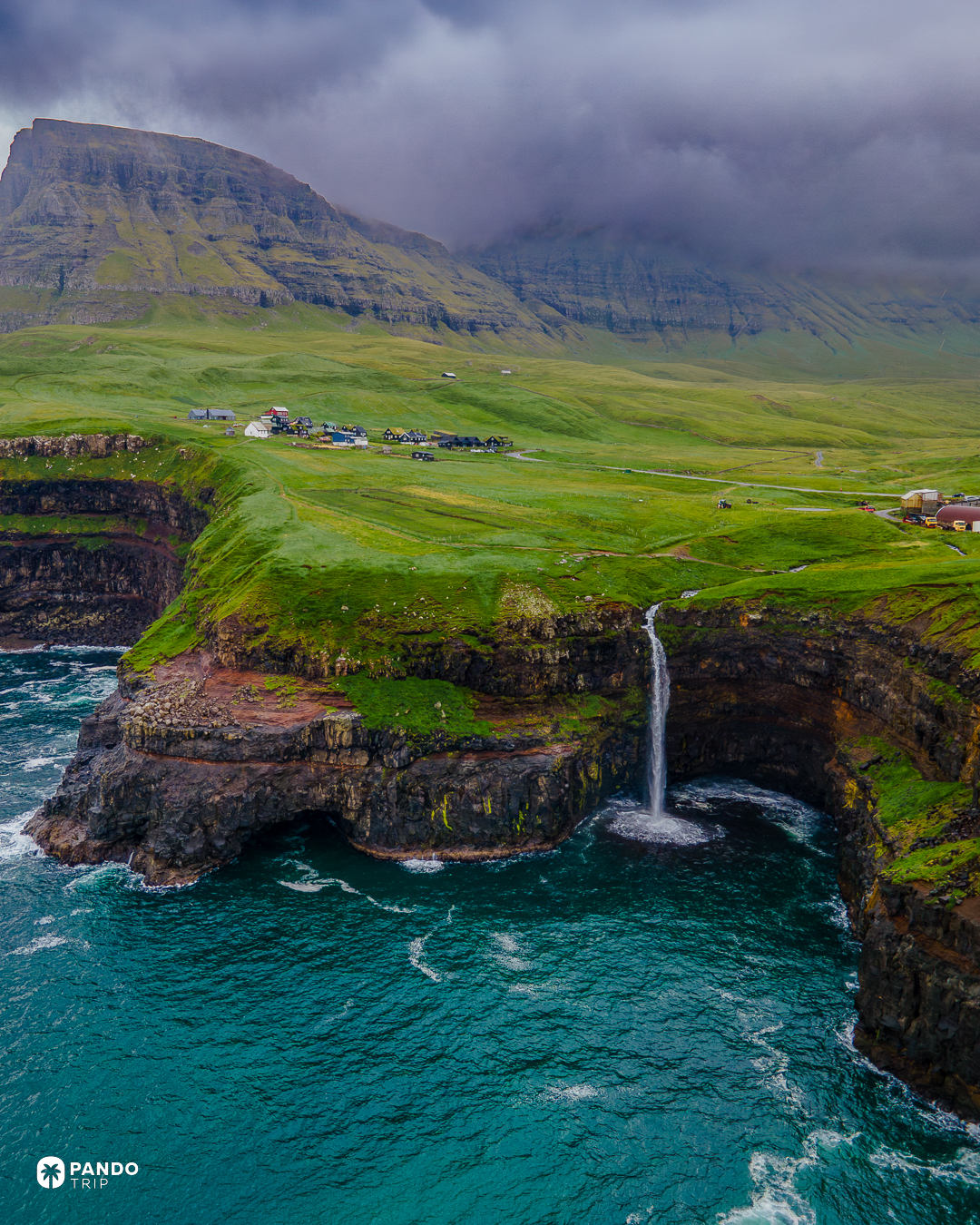 The Mulafossur waterfall dropping off the cliff straight into the Atlantic below the village of Gasadalur, Faroe Islands.