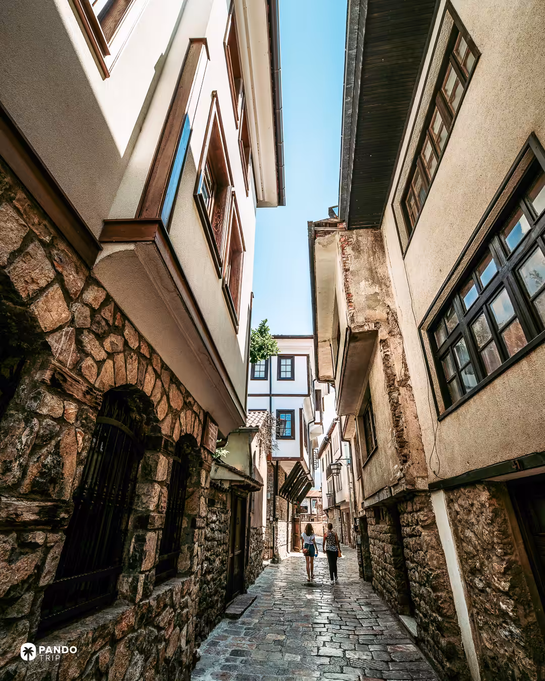 A narrow cobbled lane in Ohrid's old town between stone houses with overhanging timber upper floors.