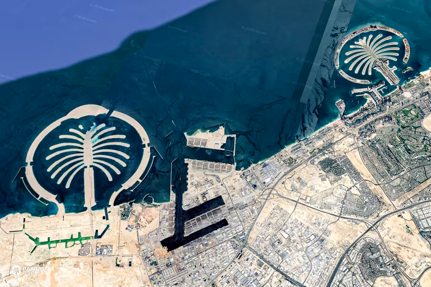 Satellite view of Palm Jumeirah and the Dubai coastline, the palm-shaped island held inside its breakwater crescent.