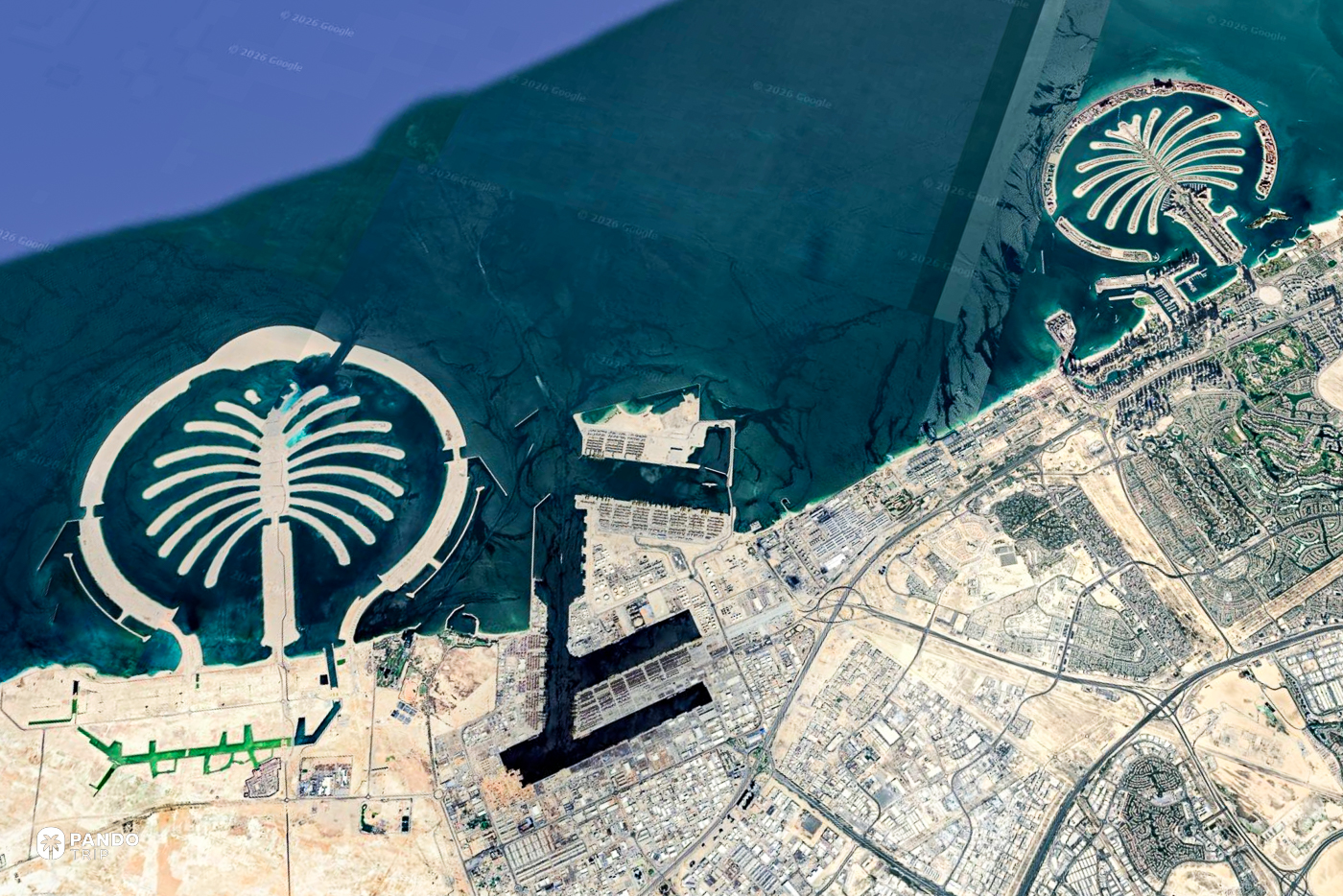 Satellite view of Palm Jumeirah and the Dubai coastline, the palm-shaped island held inside its breakwater crescent.
