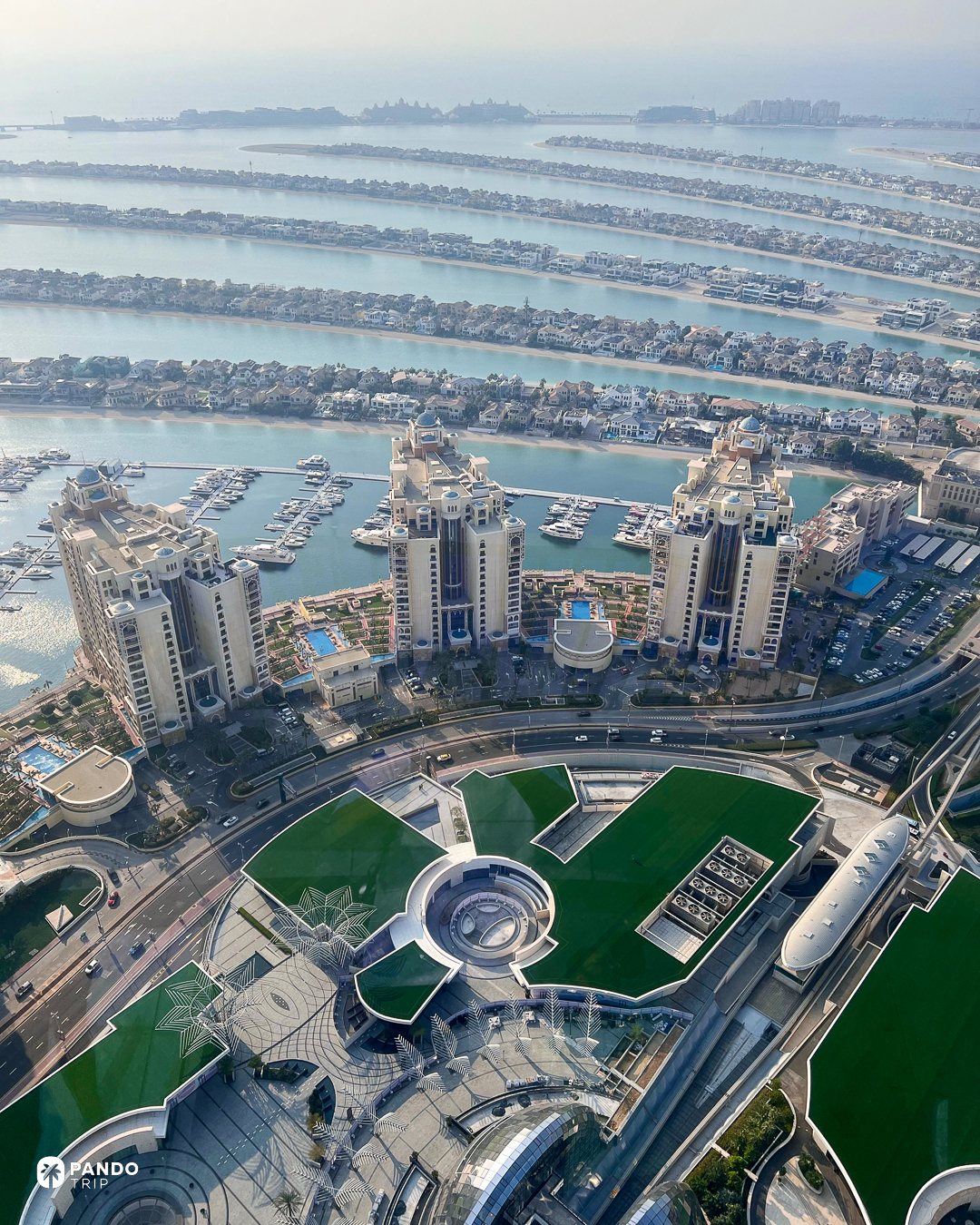 Apartment towers and marinas on Palm Jumeirah, with the fronds and open sea beyond.
