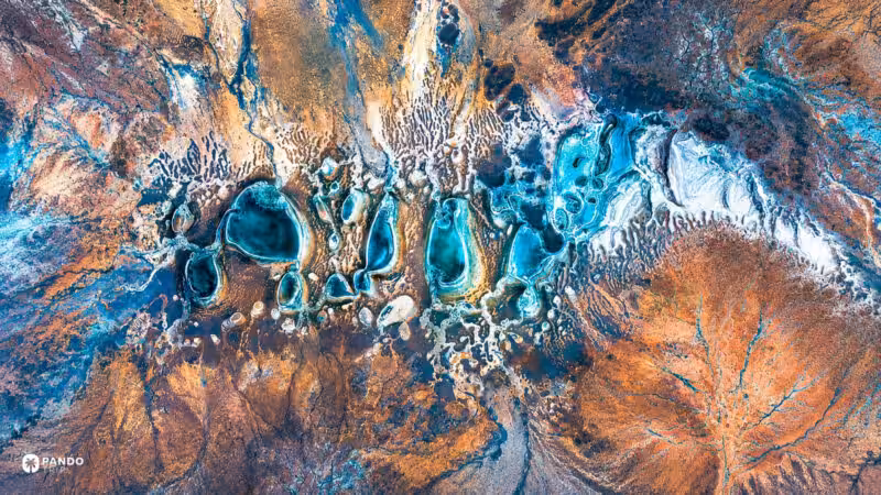 Turquoise mineral pools and rust-red terrain seen from directly above