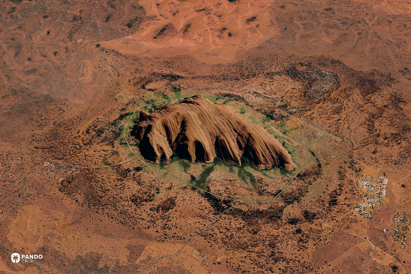Satellite view of Uluru rising from red desert, encircled by the national park's loop road.