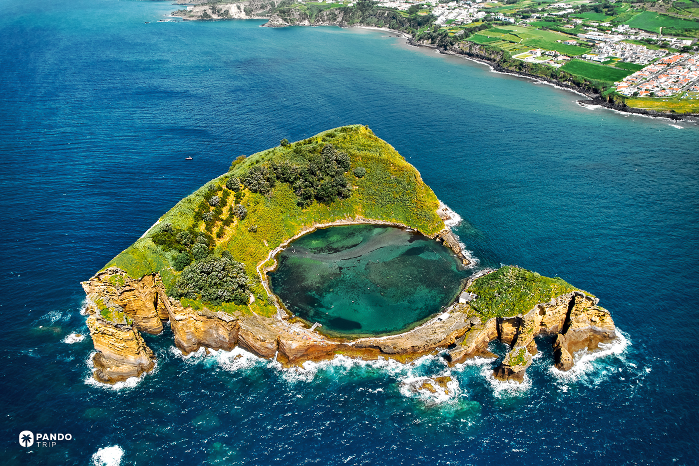The Vila Franca islet off Sao Miguel, its crater pool ringed by cliffs, with the island's coast behind.