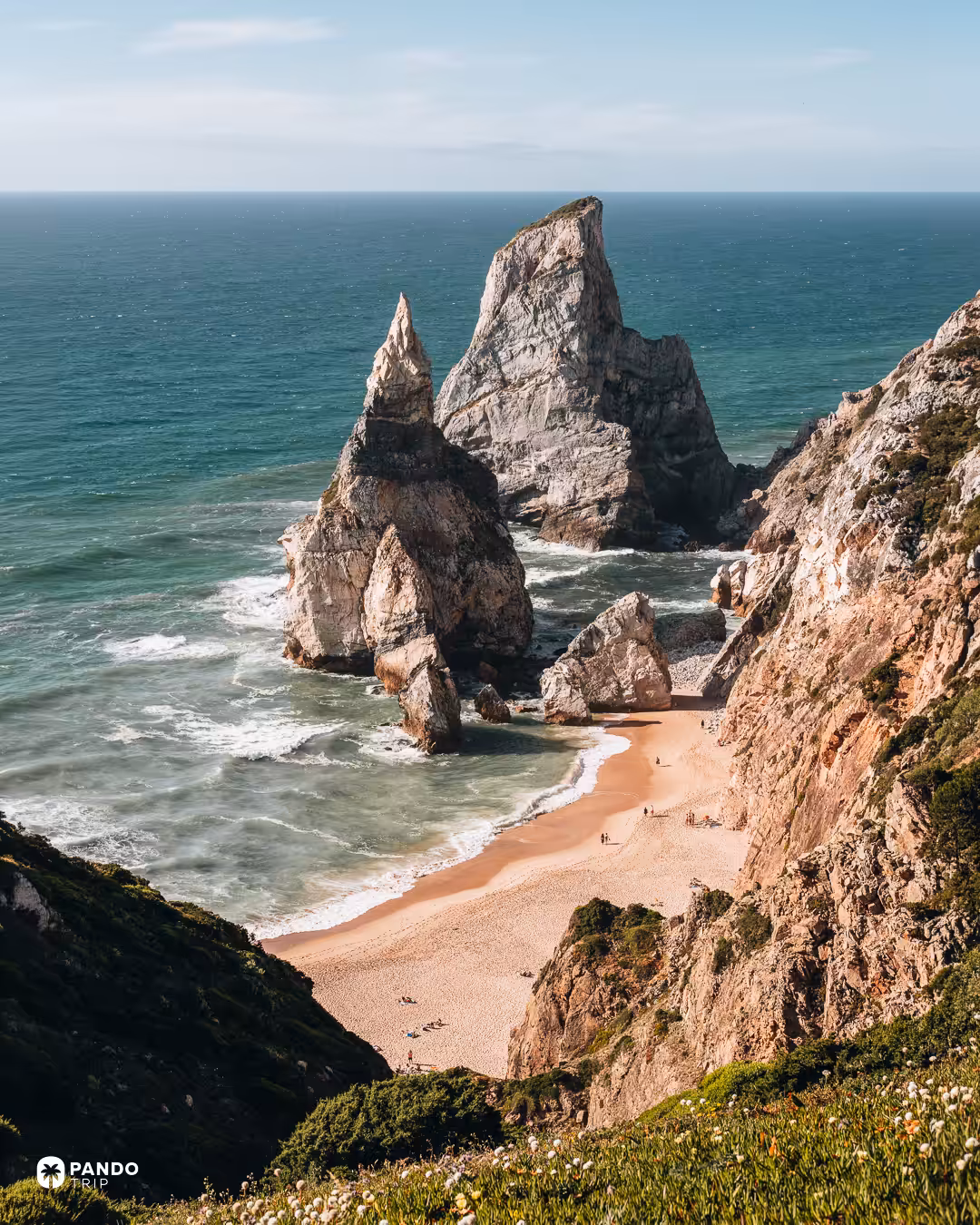 View down to Praia da Ursa and its sea stacks from the clifftop path, with people on the sand