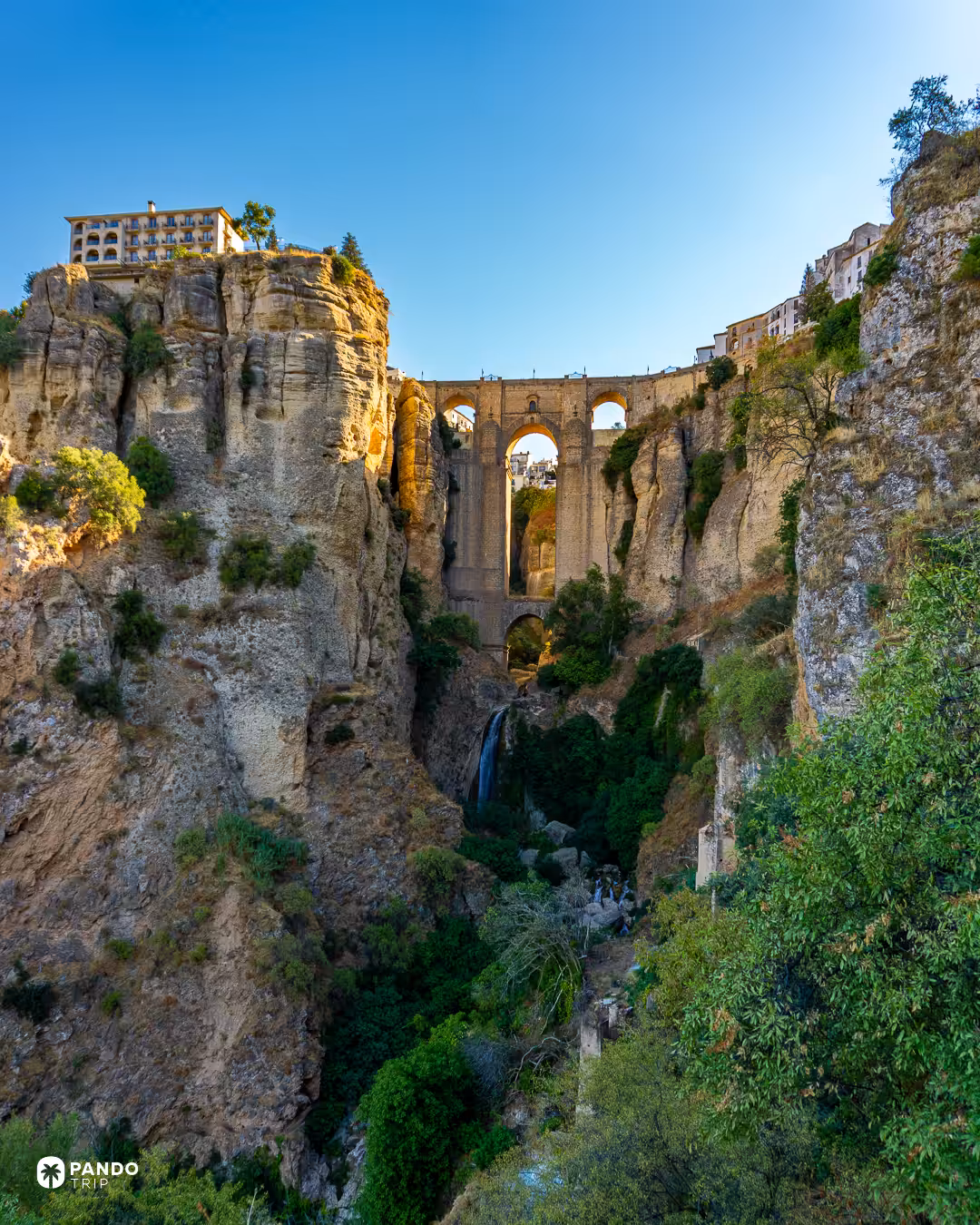 The Puente Nuevo wedged between the sheer walls of the El Tajo gorge in Ronda, with a thin waterfall falling below it.